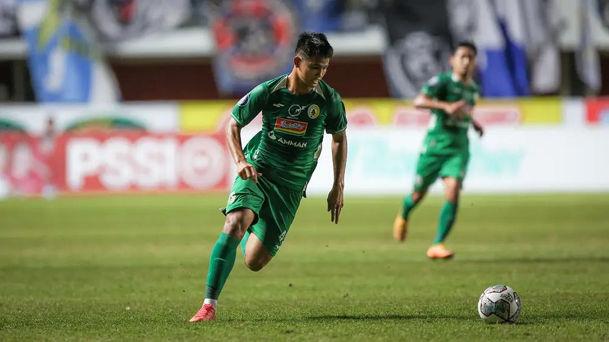 Hokky Caraka, penyerang muda PSS Sleman, beraksi di lapangan dengan latar belakang pertandingan Liga 1.